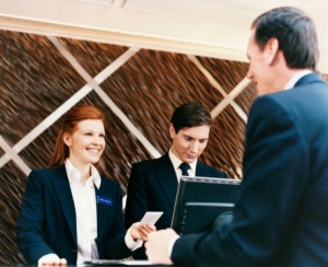 Female Hotel Receptionist Welcomes a Businessman as he Checks Into the Hotel